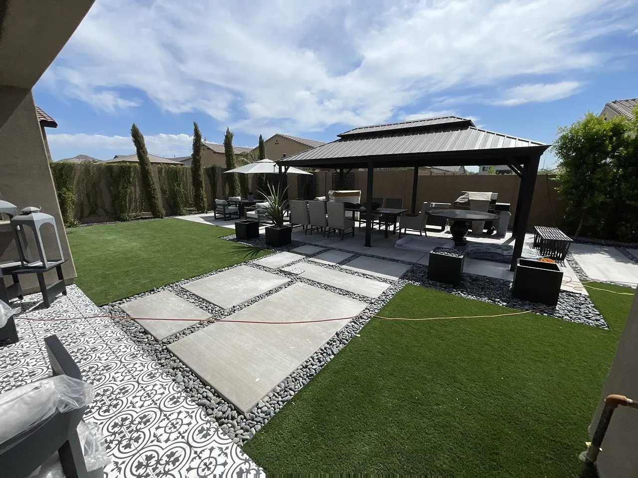 Completed outdoor living space with pavilion, kitchen, stone paving and manicured turf